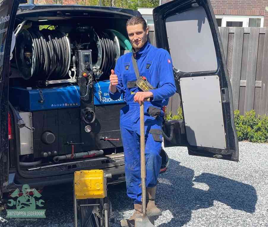 Een monteur bij de werkbus met grote hogedruk-slanghaspels, apparatuur voor hardnekkige afvoerverstoppingen in Leiderdorp