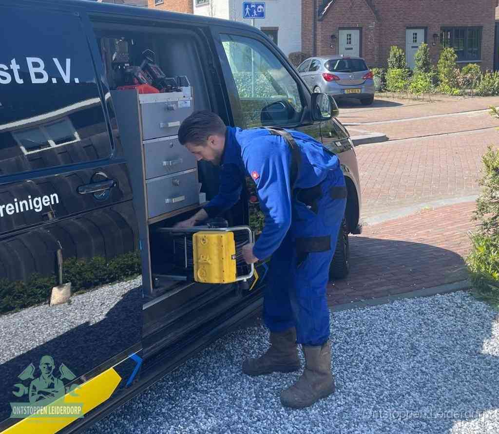 Een monteur pakt buiten op de oprit gereedschap uit de bedrijfsbus, het moment om een professional in te schakelen voor een verstopte afvoer in Leiderdorp