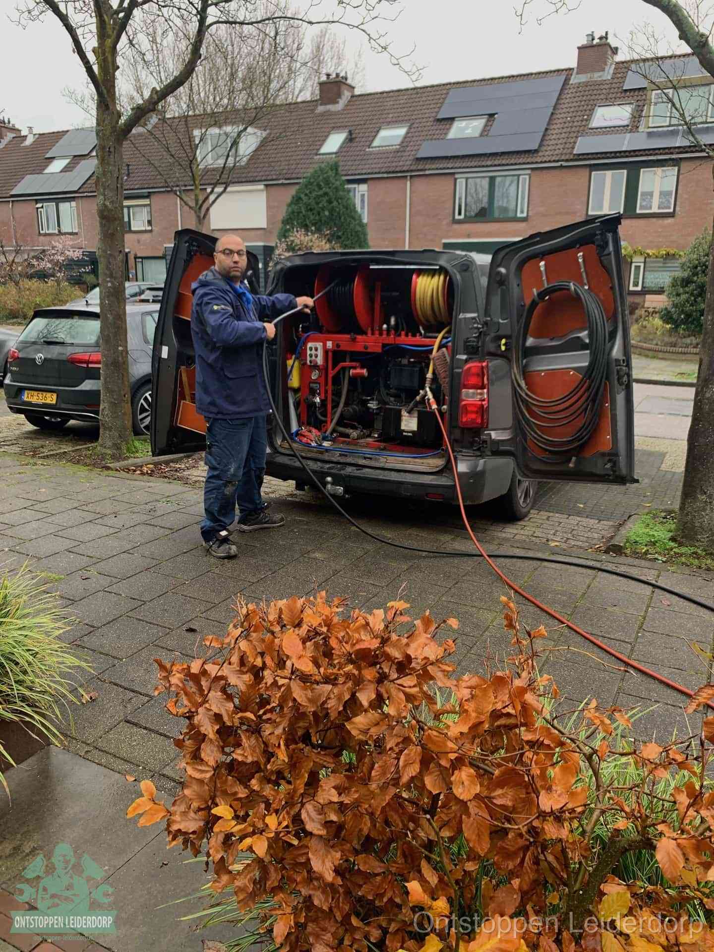 Monteur met rioolreinigingsbus levert rioolservice in de wijk in Leiderdorp