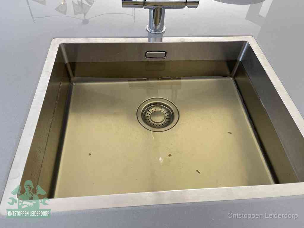 Stilstaand water in een rvs spoelbak dat niet wegloopt, een duidelijk signaal van een gootsteenverstopping in Leiderdorp