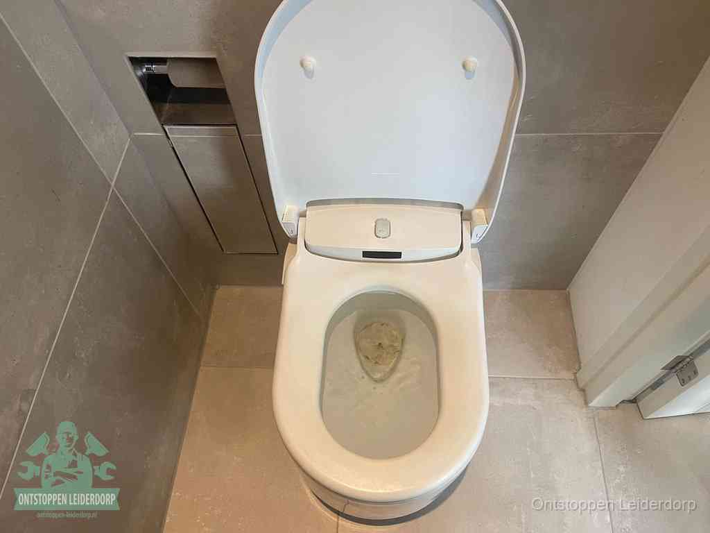 Een wit hangtoilet waarin een prop wc-papier op het water blijft drijven, een duidelijk signaal van een verstopte wc in Leiderdorp