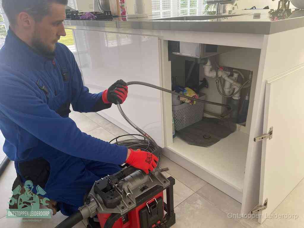 Een monteur reinigt de keukenafvoer grondig met een veermachine om terugkerende gootsteenverstoppingen te voorkomen in Leiderdorp