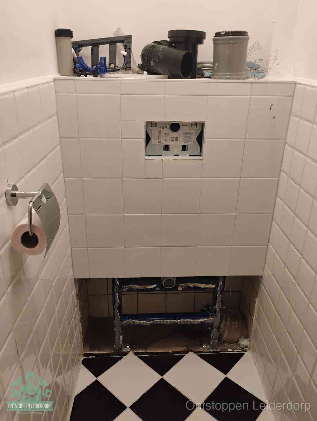 Een toiletruimte waar het hangtoilet en de inbouwreservoir-onderdelen zijn vrijgelegd voor onderhoud, periodiek nazicht voorkomt een wc-verstopping in Leiderdorp